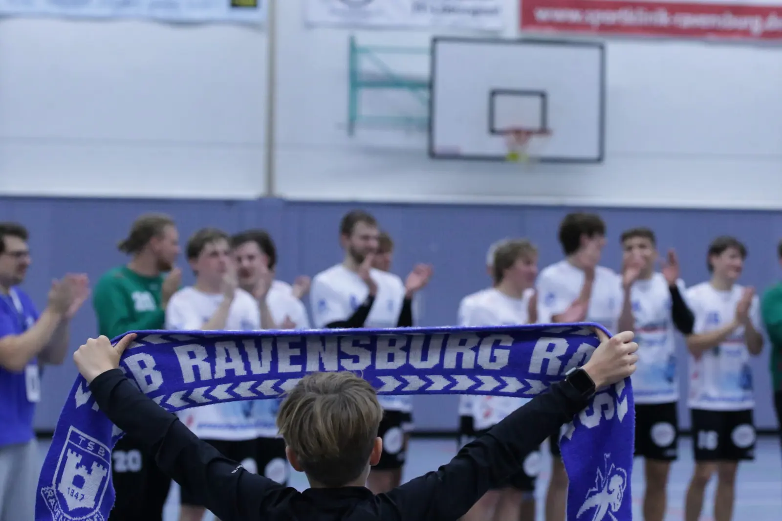 Rams-Fans mit Schal, die Mannschaft jubelt im Hintergrund
